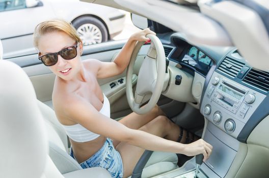 Young woman driving her car on a parking lot near shopping mall