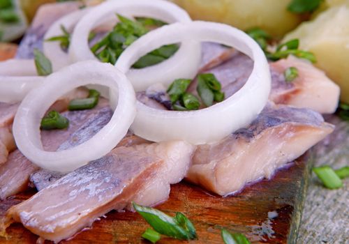 Herring with potato and  onion on a wooden table