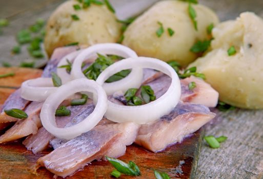Herring with potato and  onion on a wooden table
