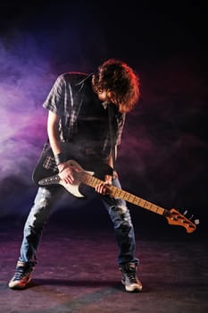 rock  bassist plays his bass on a dark background