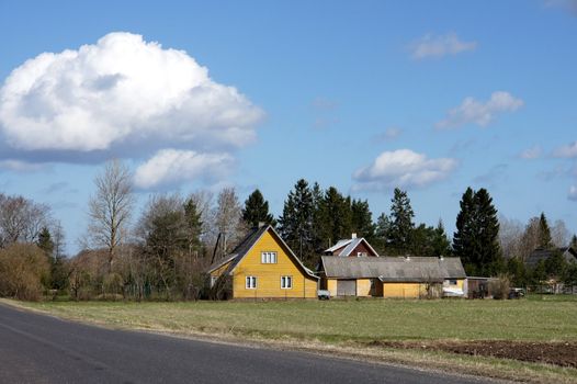 Road and the house on a background of clouds and the blue sky