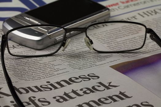 Business newspaper with a cellphone and glasses