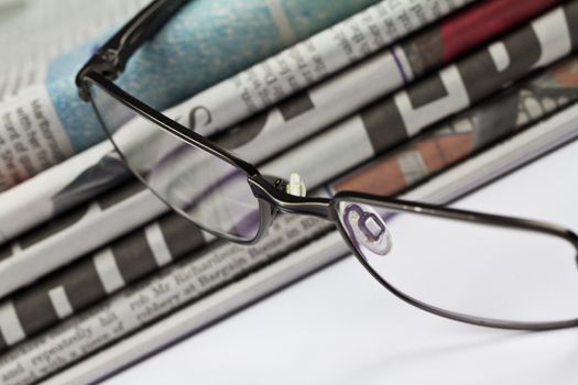 A stack of newspapers and a pair of glasses