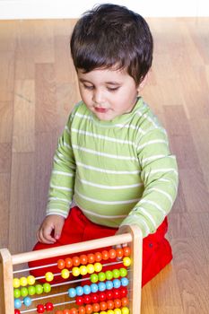 Caucasian baby in green shirt playing with bright colorful blocks