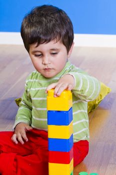 Little baby boy (2 years old) playing with toy blocks. Funny education