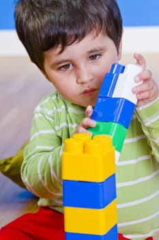 European boy playing with plastic colorful blocks