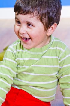 Baby in green shirt playing with bright blocks looking up in surprise