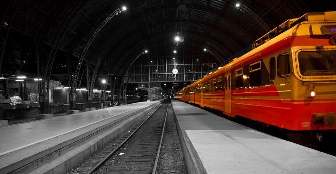 A picture of a train in a railwaystation, black white photo.With the train in color