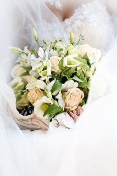 Wedding bouquet from beige roses on a background of a wedding dress