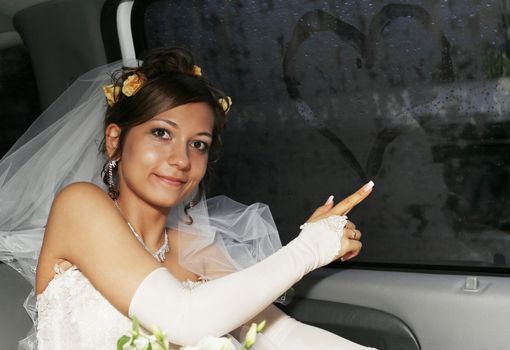 The bride in the automobile draws on glass