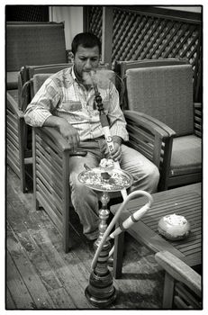 MAN SMOKING WATERPIPE, ISTANBUL, TURKEY, APRIL 17, 2012: Young Turkish man enjoying his waterpipe in a cafe, Istanbul, Turkey.