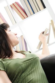 young Woman looking for a book at the bookshelf 