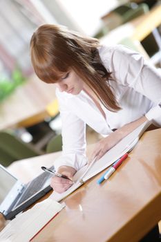 in the library -young female student with laptop and books working in a high school library