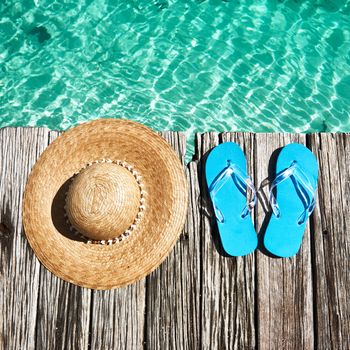 Slippers and hat at jetty by the sea