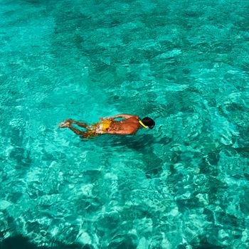 Man snorkeling in crystal clear turquoise water at tropical beach