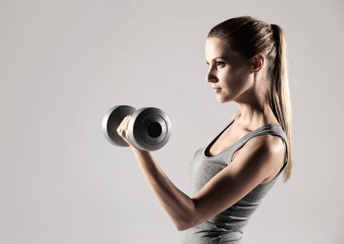 A beautiful woman raises with dumbbells 