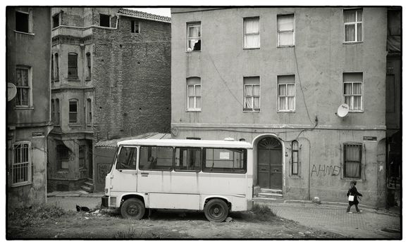 PARKED BUS FATIH, ISTANBUL, APRIL 17, 2012: Traditional housing area in the elder part of Istanbul, Turkey. A young muslim girl with scarf passing by.