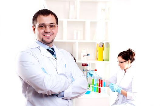 Three doctors are smiling at the camera in a doctors' office. Horizontally framed shot.