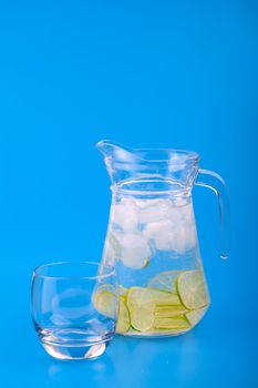 Lemonade Pitcher with ice on blue background