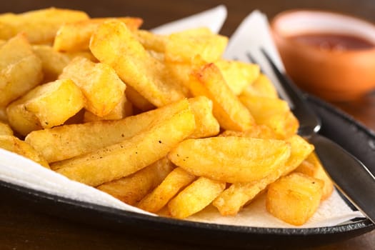 Fresh crispy homemade French fries on metallic plate with ketchup (Selective Focus, Focus one third into the fries)