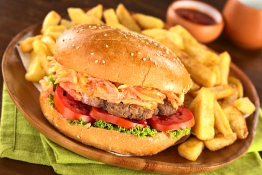 Hamburger with French fries on rustic wooden plate with ketchup (Selective Focus, Focus on the front of the hamburger)