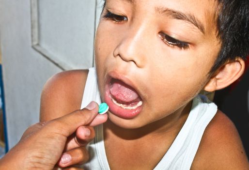 Sick young child taking medicine tablet