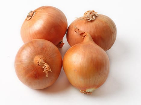 Image of four onions (Allium cepa) against a white background with shadows.