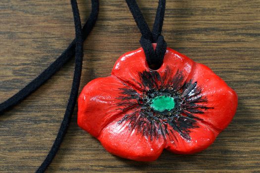 clay poppy pendent handmade on brown background