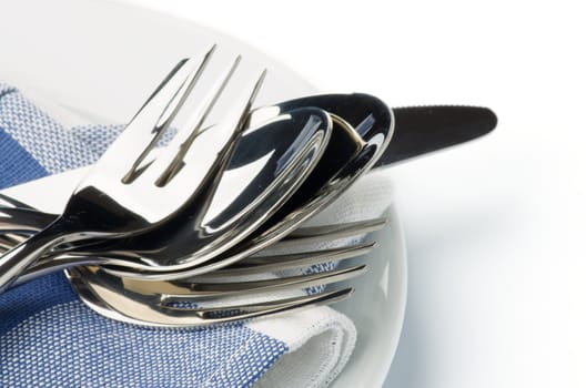 Silverware with Dessert Fork, Dessert Spoon, Table Knife, Spoon and Fork on Blue Napkin closeup on white background