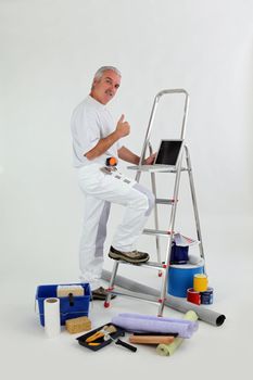 Male decorator with ladder giving thumbs-up