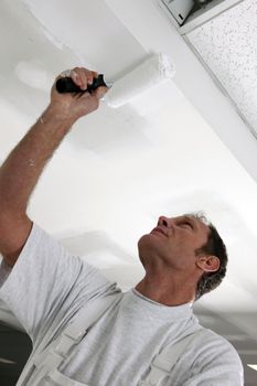 Tradesman painting a ceiling