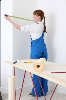 Female decorator measuring wall