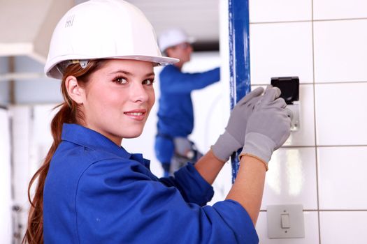 Young female electrician wiring a building