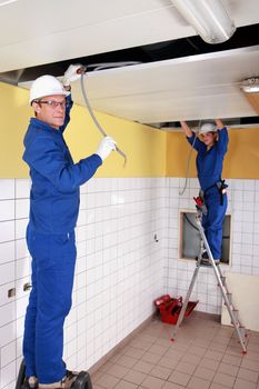 two electricians working on the ceiling