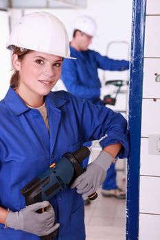 Young female electrician with a power drill