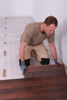 Handy-man laying wooden flooring