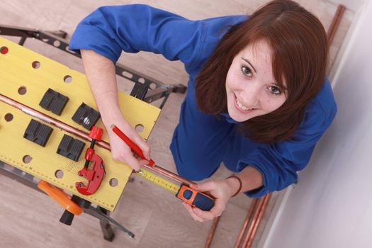 Woman measuring copper pipe