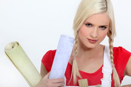 Blond woman holding rolls of wallpaper