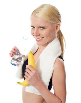 Fitness girl holding water bottle and banana with towel on her neck