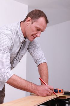Man marking a floorboard with a pencil