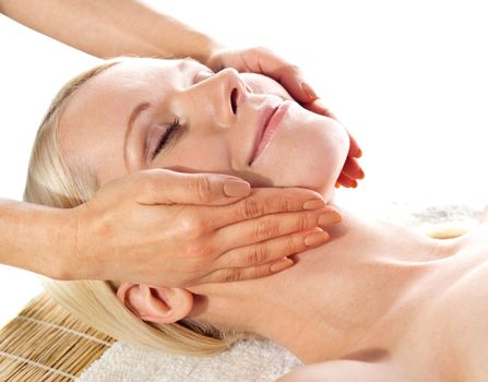 Gorgeous young woman relaxing in a spa salon during a facial massage