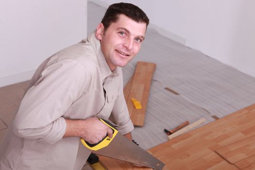 a man sawing wooden floorboards