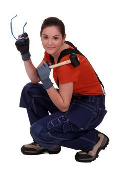 portrait of female craftsman holding hammer and protective goggles