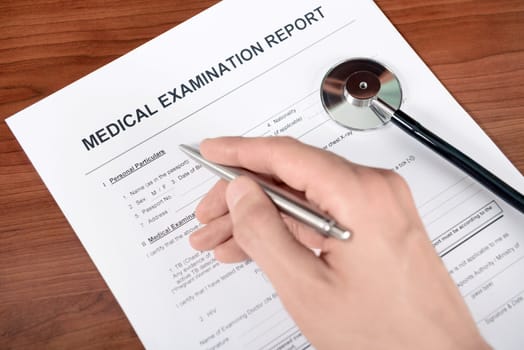 Doctor fills out blank medical report form. 