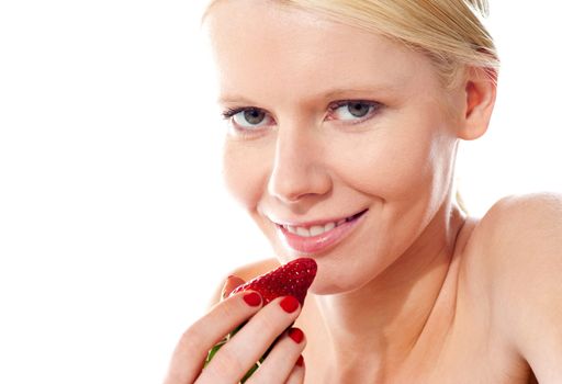 Smiling young gorgeous girl holding strawberry and looking at camera