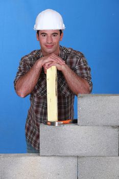 Mason stood with plank behind unfinished wall