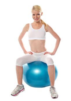 Gorgeous teenager sitting on exercise ball, smiling at camera