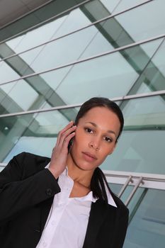 Businesswoman speaking on mobile telephone in glass building