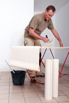 Man putting glue on wallpaper