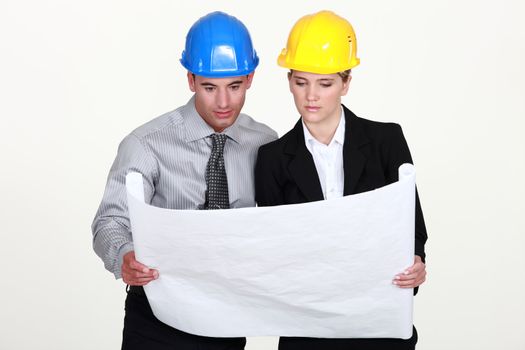 businesswoman and businessman looking at a blueprint